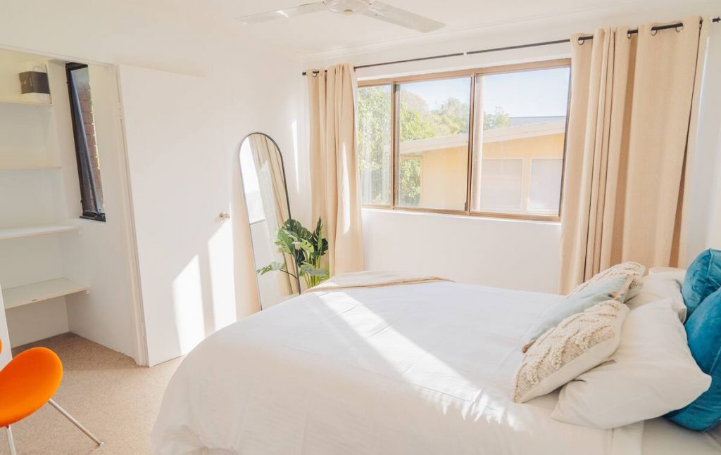 a bright and sunny bedroom with sunlight streaming through the windows