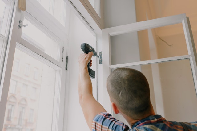 A man fixing a door with a drill