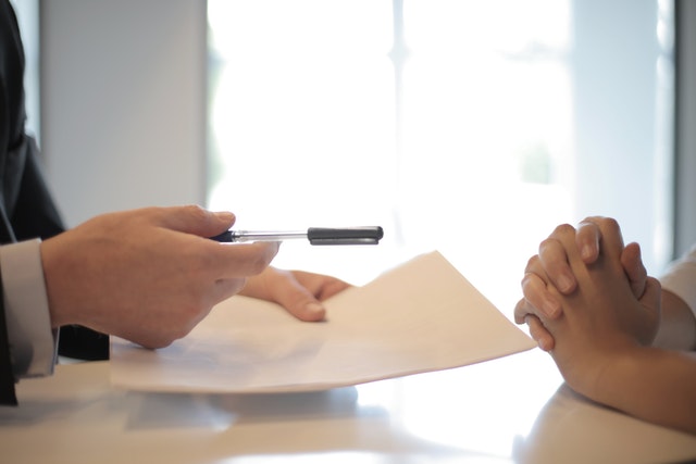 hands handing over paper to be signed